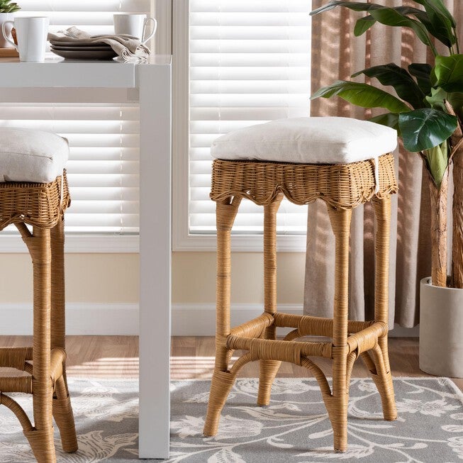 Honey rattan bar stool with scalloped woven sides and white upholstered seat cushion