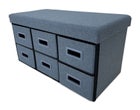 Gray storage ottoman with six drawers and cushioned top on a wooden floor